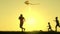A happy young father and his children run at sunset in the summer and fly a kite. Silhouette of a happy family. The
