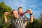 Happy young father holds his son piggyback ride on his shoulders and looking up. Little boy is sitting piggyback on shoulders his