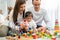 Happy young father and mother and a little daughter playing with Toy wooden blocks