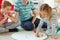 Happy young father plays with his two cheerful siblings children Board Game with colorful dices