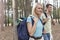 Happy young female backpacker with man hiking in woods