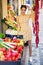 Happy young female greengrocer standing in fruits shop