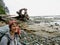 A happy young female hiker smiling and soaking wet standing on the rocky shore along the West Coast Trail, on Vancouver Island