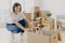 Happy young female house owner poses near cartboard box with favourite pet, have fun during day of relocation, poses in living