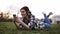 Happy young female listening music on smartphone with headphones lying on green grass in park. Girl having fun using her