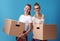 Happy young female roommates holding cardboard boxes on blue