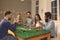 Happy young friends playing poker sitting at table with some drinks at casino themed party at home