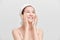 Happy young girl with clean skin and with a white towel on her head washes face