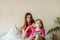 Happy young girl combing hair in the morning at home.Two teenage girls and baby sisters are caring for hair on the bed