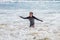 Happy Young Girl in Goggles and a Long Sleeve Bathing Suit Playing in the Ocean Surf