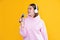 happy young girl in headphones sing in microphone on yellow background