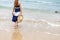 Happy young girl hold hat and walking on the beach. Summer travel, vocation, holiday concept