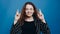happy young girl hopes for success in business crossed her fingers and closed her eyes. on a blue background