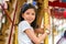 Happy Young Girl Smiling Confidentally While Sitting On a Carousel and Holding the Pole in Front of Her