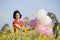 Happy young girl wear red shirt and jean hold balloon at flower garden