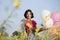 Happy young girl wear red shirt and jean hold balloon at flower garden