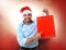 Happy young handsome man wearing santa hat holding red shopping