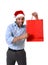 Happy young handsome man wearing santa hat holding red shopping bag