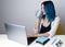 Happy young hipster woman with blue hair drink coffee or tea relax with laptop