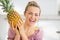 Happy young housewife holding fresh pineapple