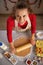 Happy young housewife rolling dough in kitchen