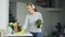 Happy young housewife in rubber gloves is listening to music through headphones and singing during clean-up at home