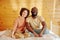 Happy young intercultural couple in homewear sitting on bed
