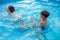 Happy young kids splashing in swimming pool