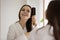 Happy young lady brushing hair after shower looking at mirror