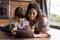 Happy young Latino mom and daughter use tablet