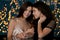 Happy young lesbian couple against defocused lights