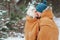 happy young loving couple walking in snowy winter forest, covered with oversize scarf