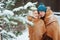 Happy young loving couple walking in snowy winter forest, covered with oversize scarf and hug.