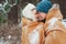 happy young loving couple walking in snowy winter forest, covered with oversize scarf and hug