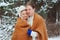 Happy young loving couple walking in snowy winter forest, covered with oversize scarf and hug