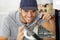 Happy young male electrician fixing oven in kitchen