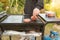 A happy young man cooking meat burgers on barbecue grill - leisure, food, people and holidays concept