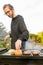 A happy young man cooking meat burgers on barbecue grill - leisure, food, people and holidays concept