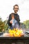 A happy young man cooking meat burgers on barbecue grill - leisure, food, people and holidays concept