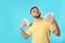 Happy young man fanning himself with money on color background