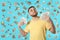 Happy young man fanning himself with money on color background