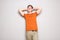 Happy young man with hands behind head leaning against gray wall