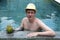 Happy young man in hat at pool with cocktail in coconut