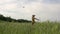 Happy young man joyfully greets an airplane flying in the sky in a wheat field in the summer at sunset. Dream, travel