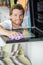 Happy young man in overall cleaning oven with rag