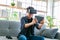 Happy young man is playing racing videogame in 3D virtual reality simulator using headset in living room