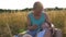 Happy young man sitting on grass at the field and playing with his baby boy. Cheerful daddy and his child having fun