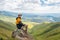 Happy young man sitting on a rock view stunning view of green valley