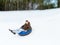 Happy young man sliding down on snow tube