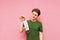 Happy young man took off his angry medical mask, isolated on a pink background, holding a gauze mask in his hand looking at her